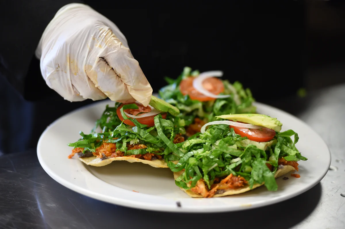 Tostadas guatemaltecas con pollo y vegetales frescos, flautas ahogadas y antojitos de Que Delicious